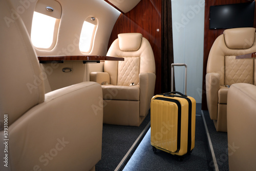 Airplane cabin with yellow suitcase. Air travel