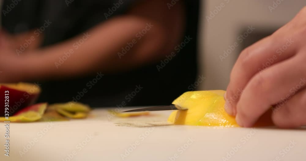 Chef Slicing A Ripe Mango For Sushi Rolls Using A Kitchen Knife In A Chopping Board.  -close up shot