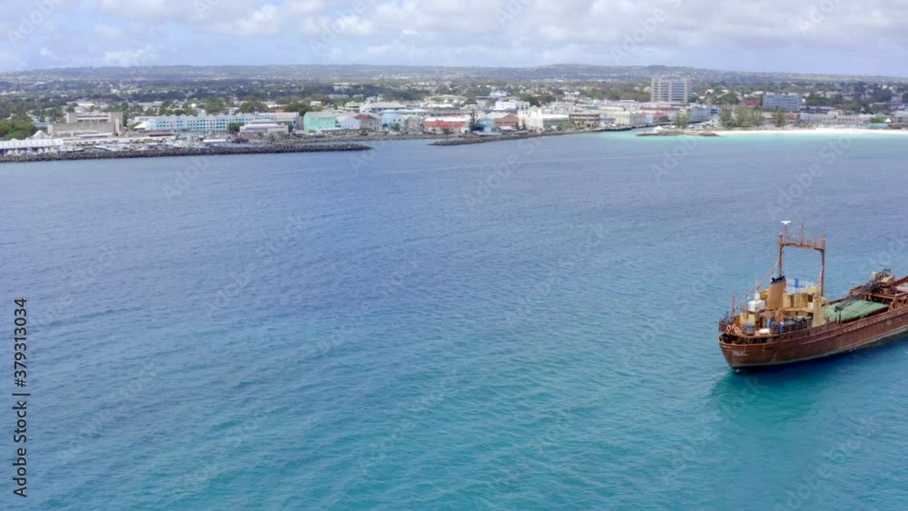 Old, rusty cargo ship in Barbados, Bridgetown docked in Carlisle Bay. Done pan from left to right covering ship and having Brownes Beach on the right side and docking space for private boats left. Old, rusty cargo ship in Barbados, Bridgetown docked in Carlisle Bay. Done pan from left to right covering ship and having Brownes Beach on the right side and docking space for private boats left.