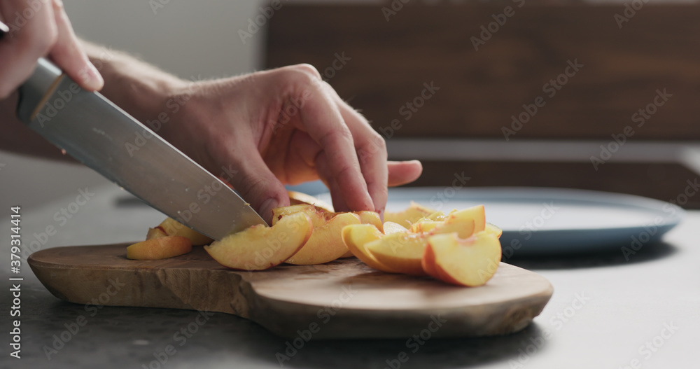 man cut fresh nectarines on a olive wood board
