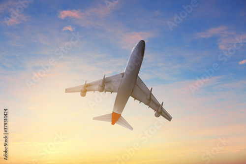 Airplane flying in cloudy sky at sunset. Air transportation