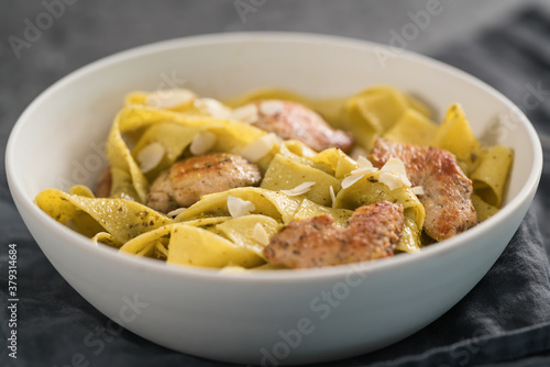 Pasta tagliatelle with chicken, pest and almonds in white bowl