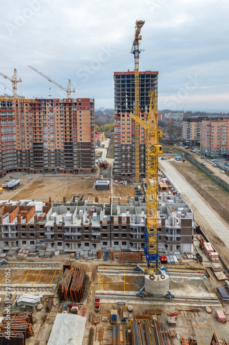 A construction site with the several unfinished multistory residential buildings on different construction stages