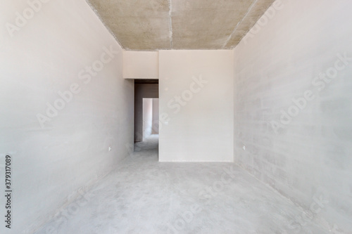 An unfinished small residential room with the plastered walls and the empty doorway