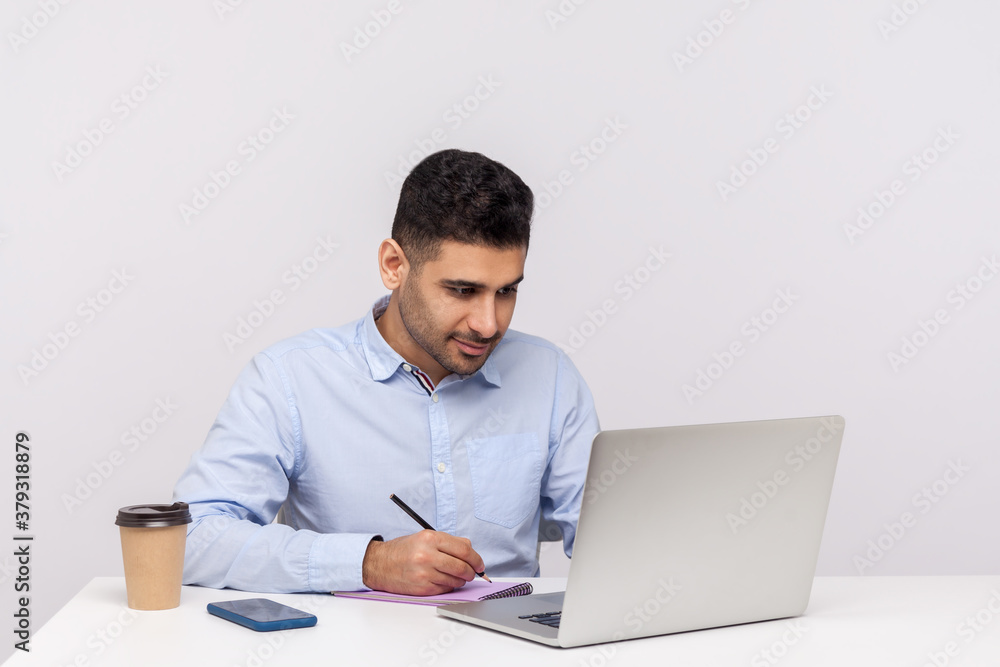 Busy man employee working on laptop and writing paper notebook, preparing report doing paperwork Busy man employee working on laptop and writing paper notebook, preparing report doing paperwork