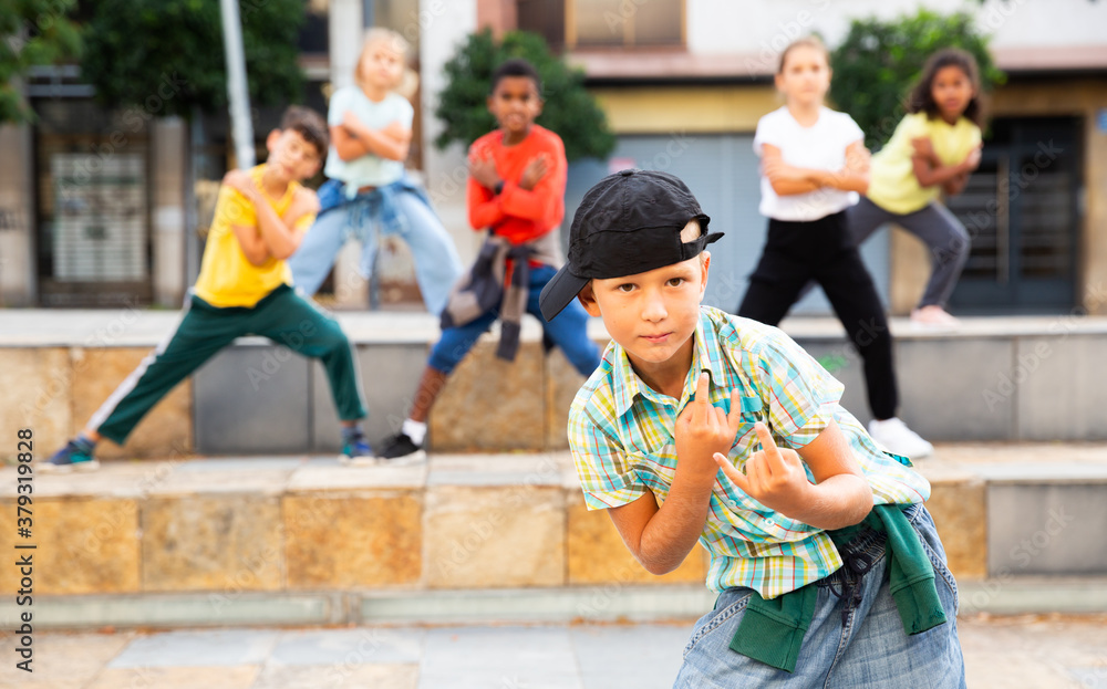 Portrait of preteen boy breakdancer dancing outdoors with children in background.