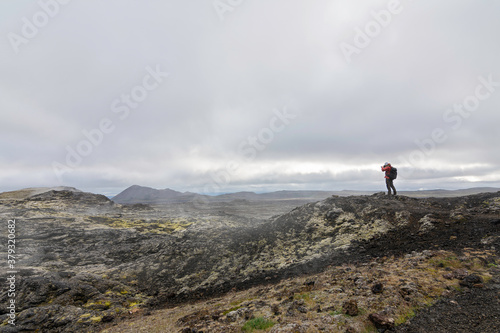 Hombre con mochila fotografiando tierras volcánicas de islandia para trabajo photo