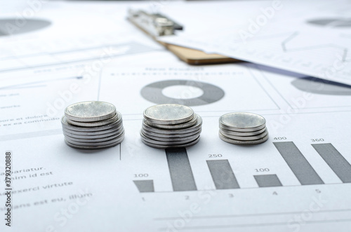 Closeup of three stacks of silver coins on the graphs and business charts.Concept of financial analyzing of budget and sales