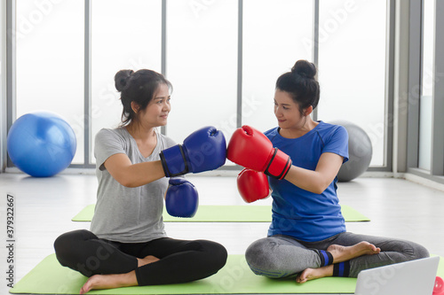 Two middle-aged Asian women doing boxing exercises in the gym.