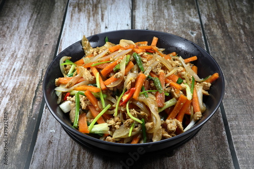 Fried and stirred sliced carrot, onion, spring onion, chilly and marinated chicken meat on the bowl. Famous traditional hot and spicy appetizer menu in Asia restaurant. 