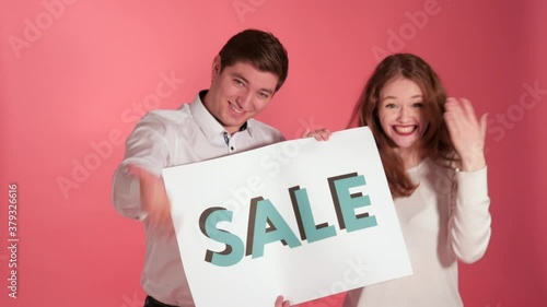 Man And Woman Invites Camera With Sale Sign, Colourful Background photo