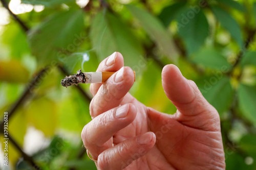  A cigarette butt is held between two fingers in a white man’s hand.