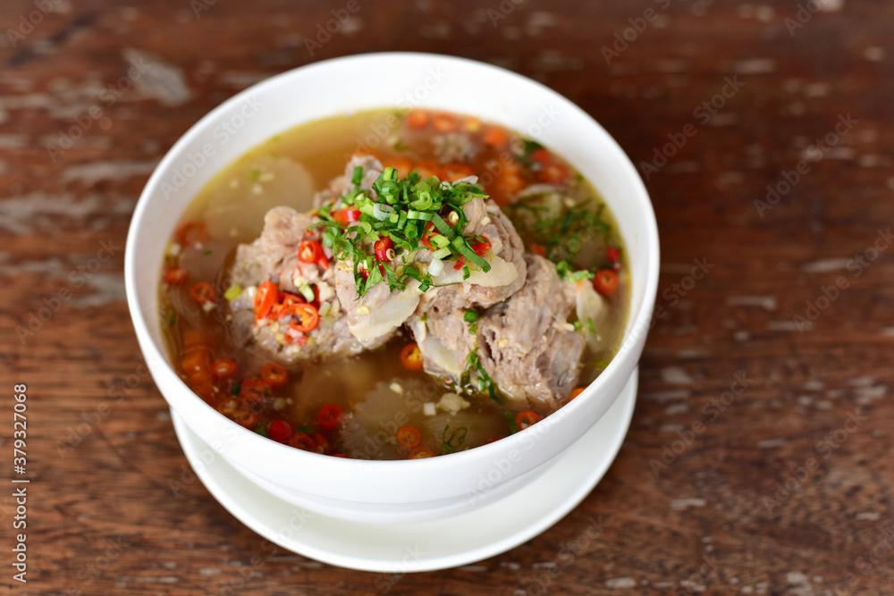 Leng boiled chilli bone food Delious. Thai food call “Leng” is boiled pork bones with spicy chili. In a white bowl, place it on a wooden table Leng boiled chilli bone food Delious. Thai food call “Leng” is boiled pork bones with spicy chili. In a white bowl, place it on a wooden table