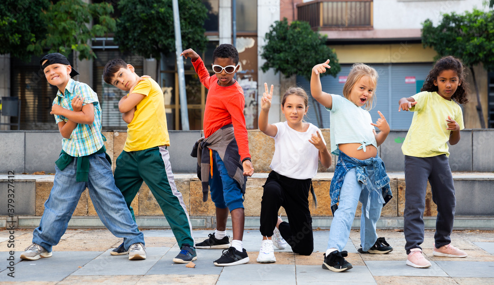 Fototapeta premium Smiling girls and boys hip hop dancers doing dance workout during open air group class