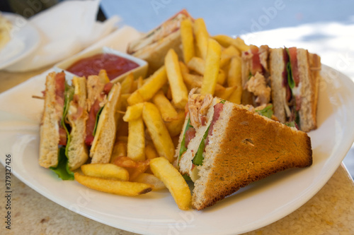 A club sandwich (clubhouse sandwich) is a sandwich of toasted bread, sliced cooked chicken or turkey, ham or fried bacon, lettuce, tomato, and mayonnaise. It is served with french fries.

