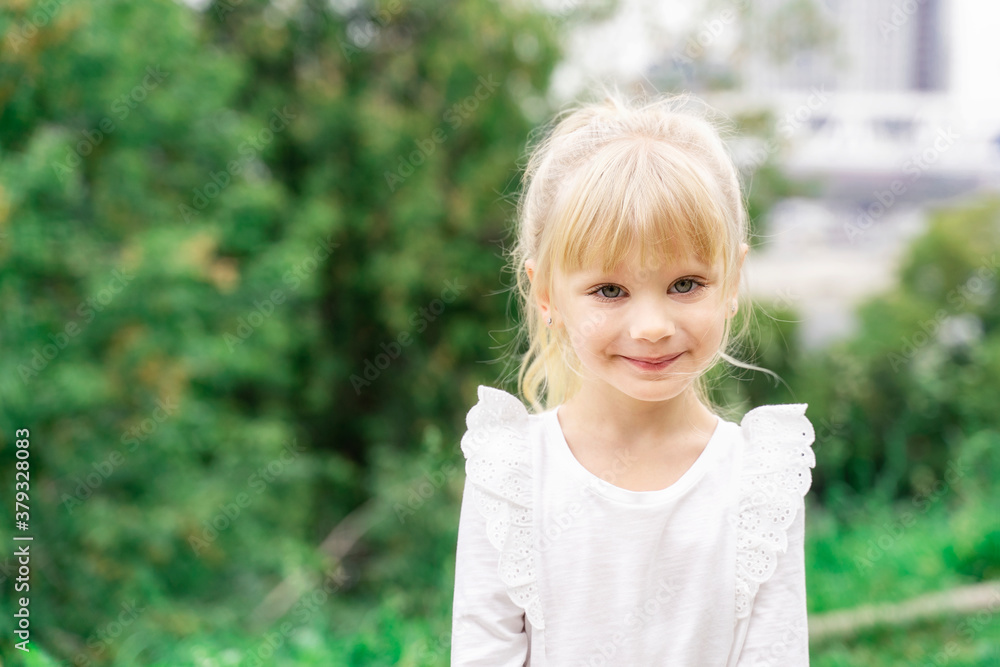 beautiful little blonde girl in white blouse smiling outdoors. copy space to the left beautiful little blonde girl in white blouse smiling outdoors. copy space to the left