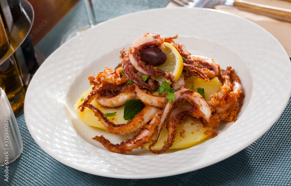 Delicious cooked squid or octopus tentacles with lemon and parsley on a plate. High quality photo