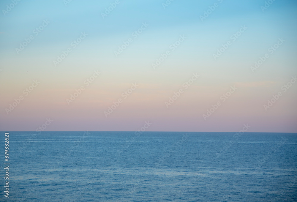 Gentle pastel sunset over the calm surface of the sea.