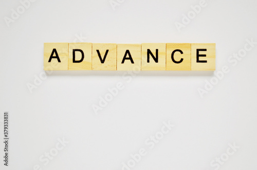 Word advance. Wooden blocks with lettering on top of white background. Top view of wooden blocks with letters on white surface