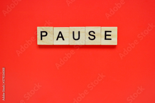 Word pause. Wooden blocks with lettering on top of red background. Top view of wooden blocks with letters on red surface