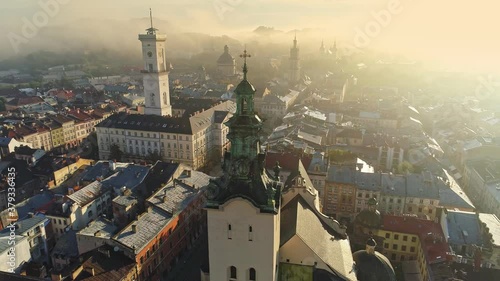 Flying over morning foggy Lviv city in Ukraine. Scenic summer aerial view of the Market Square architecture in the Old Town of Lviv, Ukraine. Town hall and Market Square bird's-eye. Summer misty