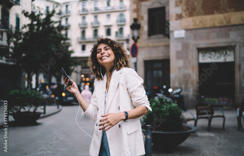 Young woman cheerfully listening to music on street