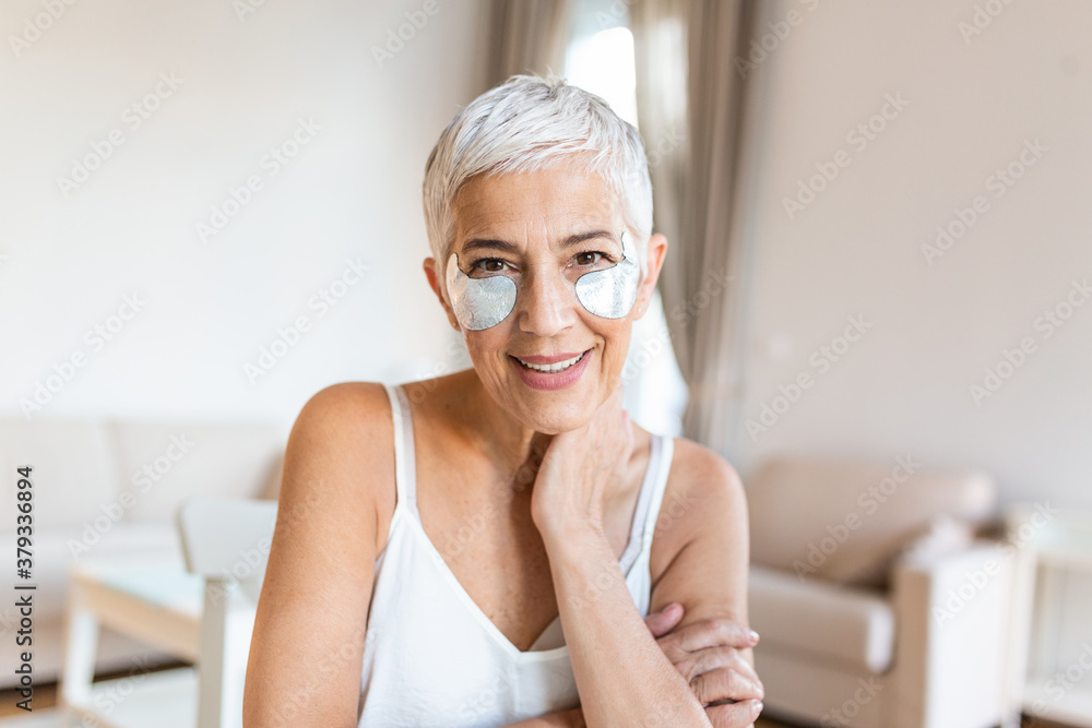 beauty, skin care and old people concept - portrait of smiling senior woman with hydrogel under-eye patches touching her face beauty, skin care and old people concept - portrait of smiling senior woman with hydrogel under-eye patches touching her face