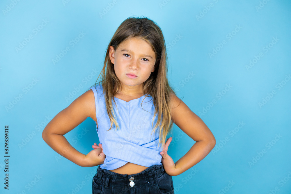 Young beautiful child girl over isolated blue background skeptic and nervous, disapproving expression on face with arms in waist Young beautiful child girl over isolated blue background skeptic and nervous, disapproving expression on face with arms in waist