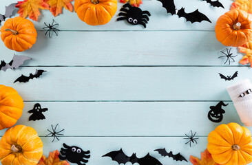 Top view of Halloween crafts, orange pumpkin, ghost, bat and spider on  pastel wooden background with copy space for text. halloween concept.