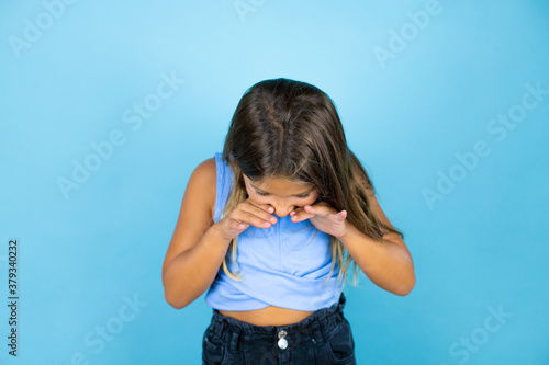 Young beautiful child girl over isolated blue background shouting and screaming loud down with hands on mouth