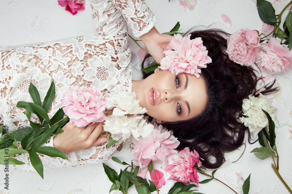 Beautiful woman with pink peony flowers, natural beauty, skin care. Perfect facial features. Girl posing on a light background Beautiful woman with pink peony flowers, natural beauty, skin care. Perfect facial features. Girl posing on a light background