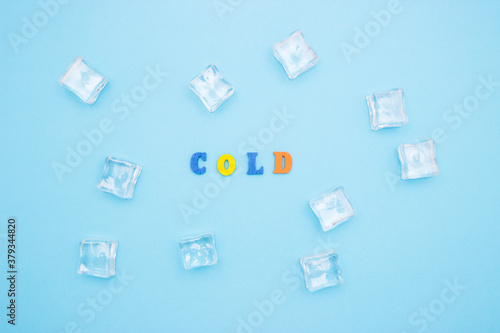 The word COLD on a blue background of wooden multicolored letters, ice cubes around the word.