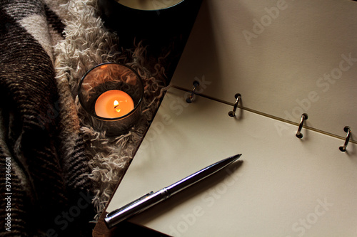 Hygge style. Warm blanket, burning candles, book for notes. vintage style, still life. photo