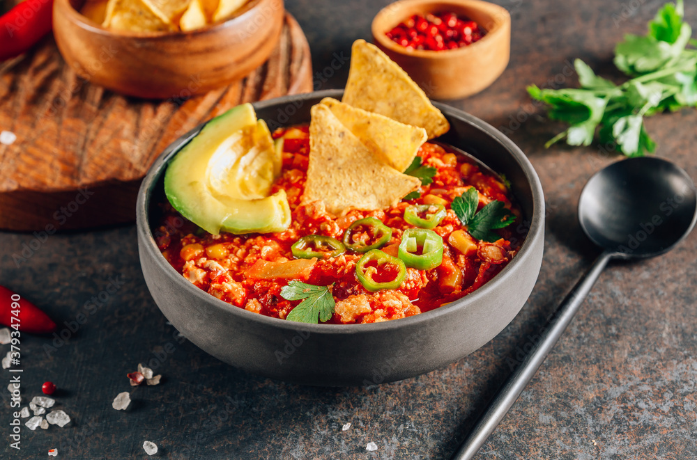 Chili Con Carne in bowl with tortilla chips on dark background. Mexican cuisine.