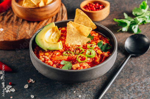 Chili Con Carne in bowl with tortilla chips on dark background. Mexican cuisine.