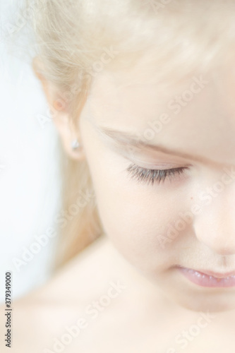Little beautiful girl child with closed eyes on a white background. Loneliness concept