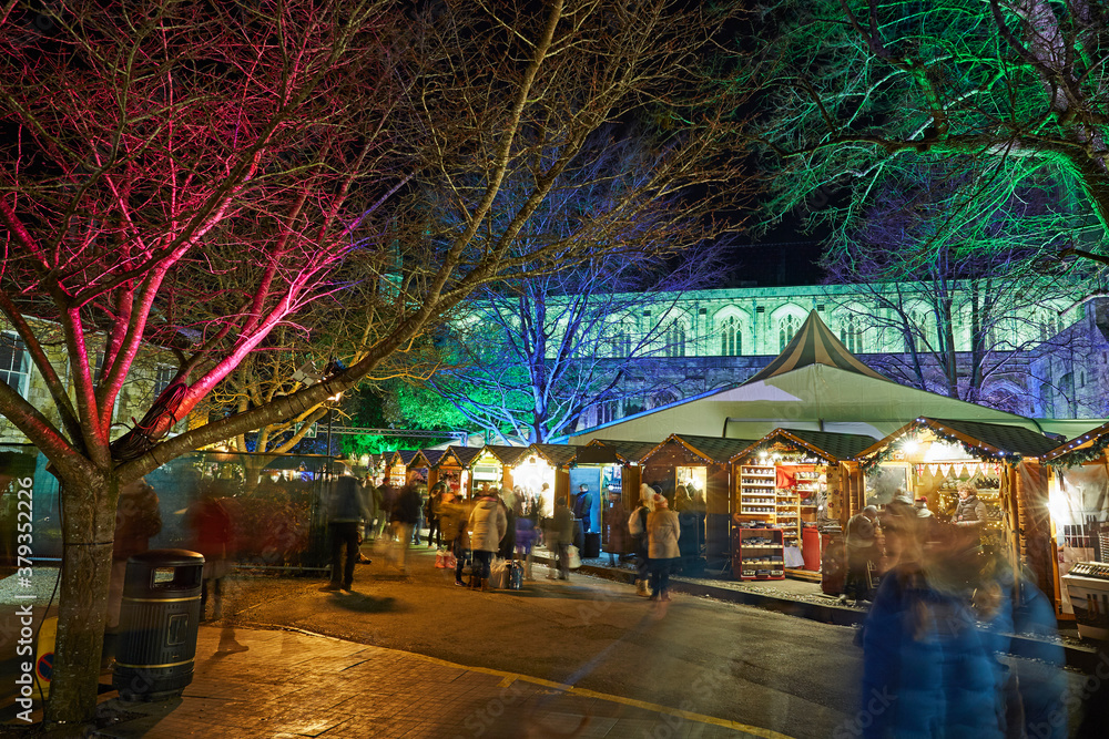 Revellers at Christmas market outside Winchester Cathedral, Hampshire, UK