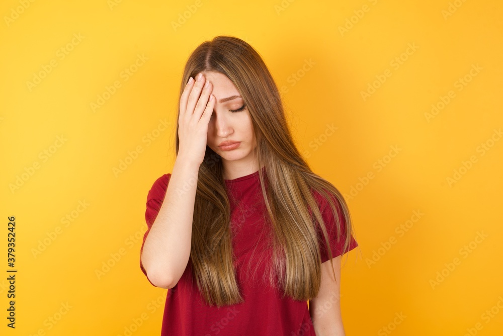 Tired overworked Beautiful Young beautiful caucasian girl wearing red t-shirt has sleepy expression, gloomy look, covers face with hand, has eyes shut, gasps from tiredness, fatigue after party Tired overworked Beautiful Young beautiful caucasian girl wearing red t-shirt has sleepy expression, gloomy look, covers face with hand, has eyes shut, gasps from tiredness, fatigue after party