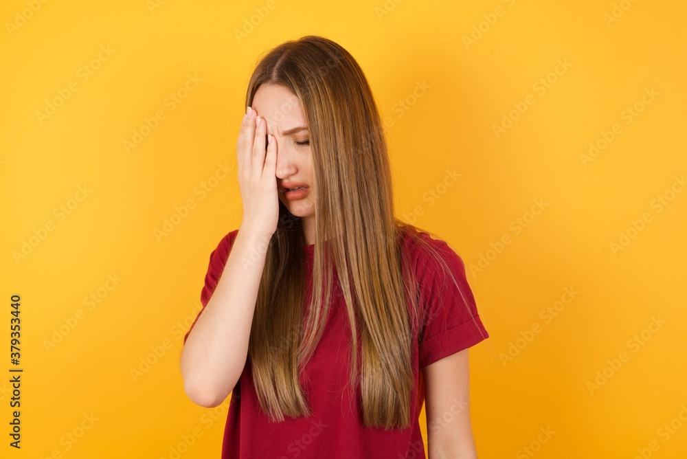 Beautiful Young beautiful caucasian girl wearing red t-shirt over isolated yellow background Yawning tired covering half face, eye and mouth with hand. Face hurts in pain. Beautiful Young beautiful caucasian girl wearing red t-shirt over isolated yellow background Yawning tired covering half face, eye and mouth with hand. Face hurts in pain.
