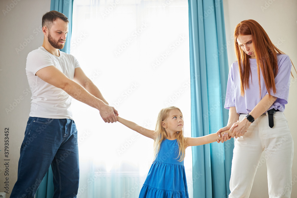 Fototapeta premium young mother and father share child girl, divided kid, going to ber divorced. they have amily conflict, scandal, quarrel between husband and wife