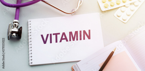 The words VITAMIN are written in a notebook, a medical concept