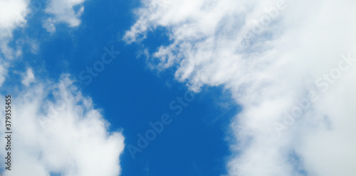 Cloudy Sky background. Beautiful clear blue sky with soft fluffy white clouds in sunny day. Elegant cloudy blue sky texture  wallpaper. Landscape image. Flat puffy shape Cumulus Clouds in daylight