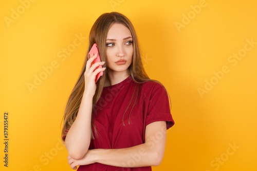 Sad Beautiful Young beautiful caucasian girl wearing red t-shirt over isolated yellow background. Communication concept.