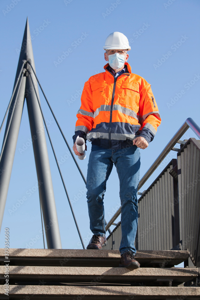 Architect or engineer with face mask and protective clothing walking downstairs Architect or engineer with face mask and protective clothing walking downstairs