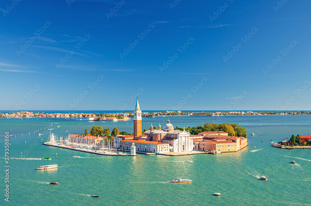 Aerial panoramic view of San Giorgio Maggiore island with Campanile San Giorgio in Venetian Lagoon, sailing boats in Giudecca Canal, Lido island, blue sky background, Venice city, Veneto Region, Italy