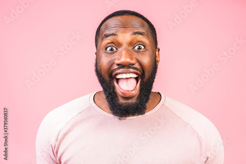 Surprised amazed african american man guy in casual isolated on pink background studio portrait. People lifestyle concept. Mock up copy space. Keeping mouth open.