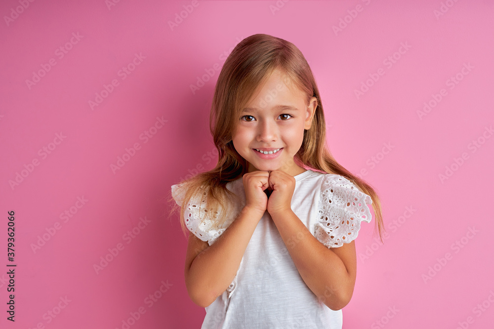 pretty caucasian little girl is dreaming about new toy, she has a mysterious look, wearing white blouse, isolated pink background pretty caucasian little girl is dreaming about new toy, she has a mysterious look, wearing white blouse, isolated pink background