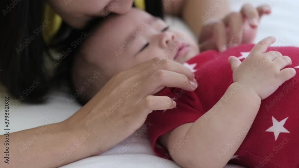 Asian mother takecare her cute baby sleeping and kissing on bed at home. Asian mother takecare her cute baby sleeping and kissing on bed at home.
