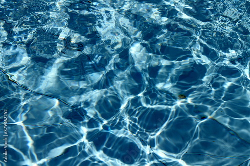 texture of pool water with light bending from the bottom due to sun color
