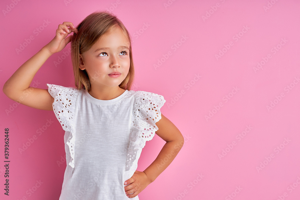 thoughtful little caucasian girl is looking away, dreaming, wearing white blouse, isolated over pink background thoughtful little caucasian girl is looking away, dreaming, wearing white blouse, isolated over pink background